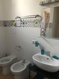 bagno con lavandino, servizi igienici e specchio di [VICINO AL MARE] Bougainvillea House a Marina di Casalvelino