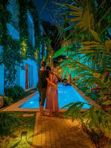 a couple standing in front of a pool at night at Olbil Hotel Boutique in Valladolid