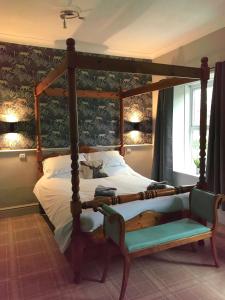a bedroom with a four poster bed with a chair at Red Lion Coaching Inn in Redbourne