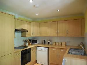 a kitchen with wooden cabinets and a stove top oven at Pinesmoke in Killin