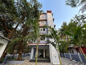 uma casa branca com palmeiras em frente em Serenova by Dia Hotels em Calangute
