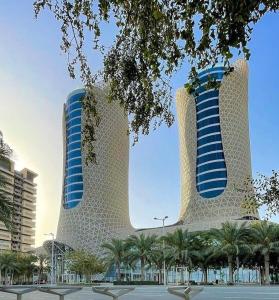 two tall buildings with palm trees in front of them at Century Marina Hotel - Lusail in Lusail
