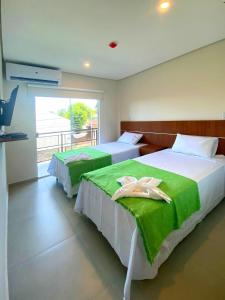 um quarto com 2 camas com lençóis verdes e uma janela em VIVARIUM APART HOTEL em Assunção