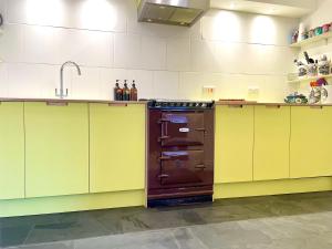 a kitchen with yellow cabinets and a sink and an oven at Paramount Apartments Ilfracombe, arty seaside holiday apartments in Ilfracombe