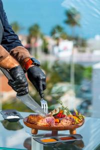 a person in gloves cutting a pizza with a knife at Essence Hotel Boutique in Torremolinos
