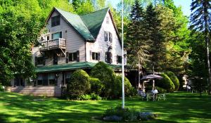 a large house with people sitting on the lawn at Slide Mountain Forest House in Oliverea