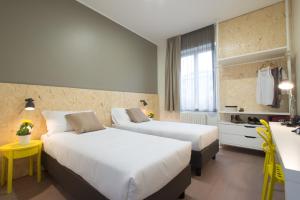 a hotel room with two beds and a desk at B&B Hotel Milano Ornato in Milan