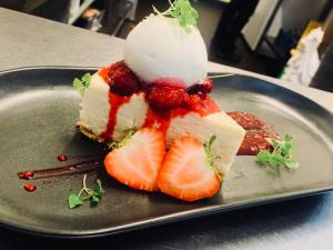 un morceau de gâteau avec des fraises et de la crème glacée sur une assiette dans l'établissement The Crossroads Inn, à Halifax