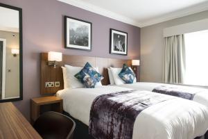 two beds in a hotel room with purple walls at The Swan by Innkeeper's Collection in Coleshill