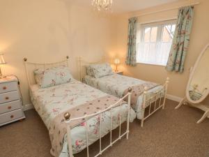 a bedroom with two beds and a mirror at Holly Cottage in Ventnor