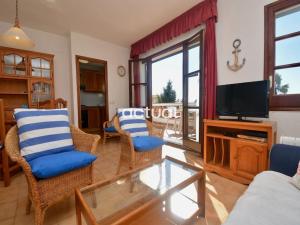 een woonkamer met een tv en een bank en stoelen bij ALBA V 2º 1ª in S'Agaro