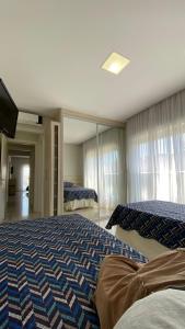 um quarto com duas camas e uma televisão em Apartamento Costão das Gaivotas - Praia do Santinho - Ingleses - Florianópolis em Florianópolis