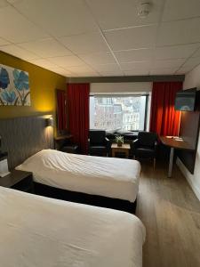 a hotel room with two beds and a window at City Hotel Tilburg in Tilburg