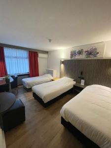 a hotel room with two beds and a couch at City Hotel Tilburg in Tilburg