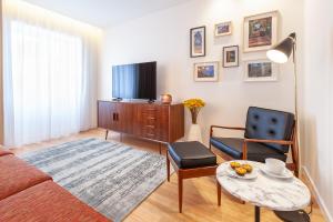 a living room with a couch and a tv and a table at Sé Apartamentos - Avenida Residence in Braga