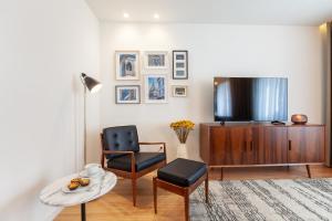 a living room with a tv and a chair and a table at Sé Apartamentos - Avenida Residence in Braga