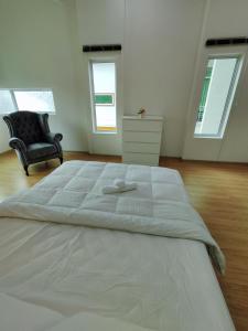 Cette chambre comprend un grand lit blanc et une chaise. dans l'établissement Ipoh Lake View Cozy Home Big House, à Lahat