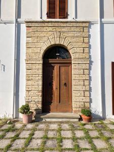 une porte en bois sur un bâtiment en briques avec deux plantes dans l'établissement Villa dei Trabocchi - Accogliente casale per famiglie che affaccia sul mare, à Ortona
