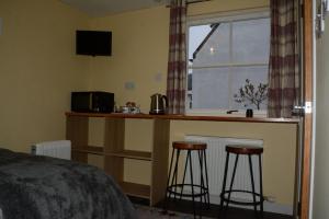 a bedroom with a bed and a kitchen with two bar stools at Room at the Back, 2 George Street in Avoch