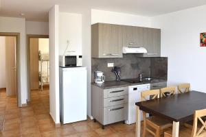 una cucina con tavolo, frigorifero, tavolo e sedie di Punta di Mare a Linguizzetta