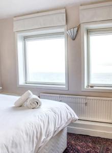 1 dormitorio con 2 ventanas y 1 cama blanca en Fisherman's Cottage, en Cockenzie
