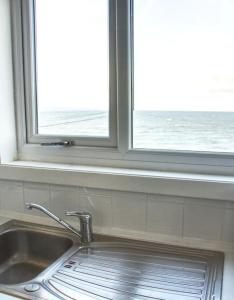 a window above a kitchen sink with a view of the ocean at Fisherman's Cottage in Cockenzie