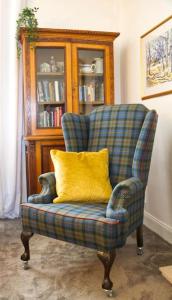 a chair with a yellow pillow in a living room at Fisherman's Cottage in Cockenzie