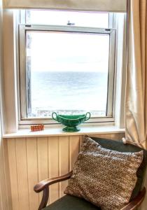 a green bowl sitting in a window with a chair at Fisherman's Cottage in Cockenzie