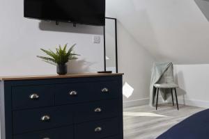 a bedroom with a dresser with a tv on top of it at Homebird Property - Ash Tree House in Leeds