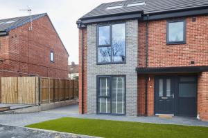 a red brick house with a black door at Homebird Property - Ash Tree House in Leeds