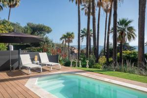einen Pool mit 2 Stühlen und einem Sonnenschirm in der Unterkunft Paradis en Rez de jardin - Standing - Vue Mer - piscine privée in Vallauris