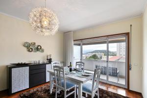 comedor con mesa, sillas y lámpara de araña en Sé Apartamentos - Casa Cecília, en Braga