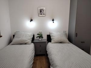 2 łóżka w pokoju z białymi ścianami i światłami w obiekcie Dom Przy Lesie na Warmii w mieście Woryty
