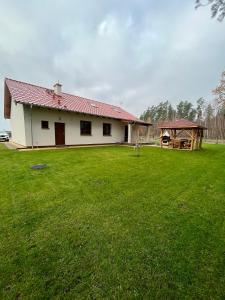 Casa blanca con techo rojo y patio grande en Dom Przy Lesie na Warmii, en Woryty