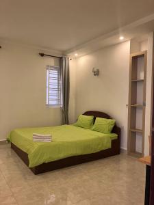een slaapkamer met een bed met groene lakens en een raam bij Murrayrata in Phnom Penh