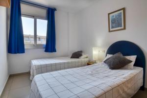 2 camas en una habitación con cortinas azules y ventana en El Moll, en L'Escala