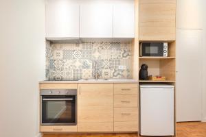 a kitchen with a refrigerator and a microwave at Sé Apartamentos - Casa Do Raio Center Apartments in Braga
