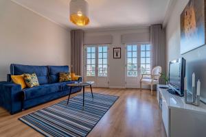 un salon avec un canapé bleu et une télévision dans l'établissement Sé Apartamento - Casa do Chafariz, à Braga