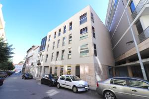 a white car parked in front of a building at Sé Apartamentos - Cruz de Pedra Apartment in Braga