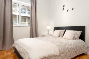 een witte slaapkamer met een groot bed met witte kussens bij Sé Apartamentos - Casa Do Raio Center Apartments in Braga