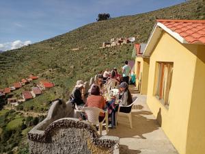a group of people sitting at a table on a hill at Hostal Inca Uma in Comunidad Yumani