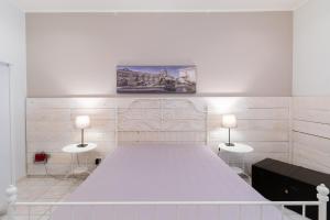 シラクーサにあるSyracuseApartments IL PIAVE di SIRACUSA Appartamento per 6 persone vicino ad ORTIGIA a 200m dal MAREの白いベッドルーム(ランプ2つ付きの大型ベッド1台付)