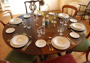 a wooden table with white plates and silverware on it at Duleep Singh Barn in Botesdale