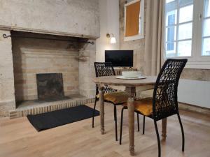 uma mesa e cadeiras numa sala de estar com lareira em Studio * Le Petit Nicolas * em Périgueux