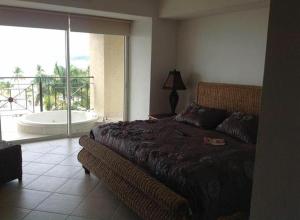 a bedroom with a bed and a large window with a tub at Bay view grand residencial - 3 beds-501 in Ixtapa