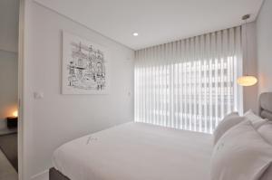 a white bedroom with a bed and a window at Sé Apartamentos - Luxury Apartment in Braga