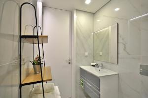 a white bathroom with a sink and a mirror at Sé Apartamentos - Luxury Apartment in Braga
