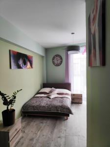 sypialnia z łóżkiem i zegarem na ścianie w obiekcie Apartament HELLADA w mieście Krynica Zdrój