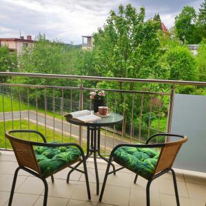 balkon ze stołem i 2 krzesłami na balkonie w obiekcie Apartament HELLADA w mieście Krynica Zdrój
