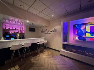 ジーリクゼーにあるHotel van Oppenのスツール付きのバーと壁掛けテレビが備わります。